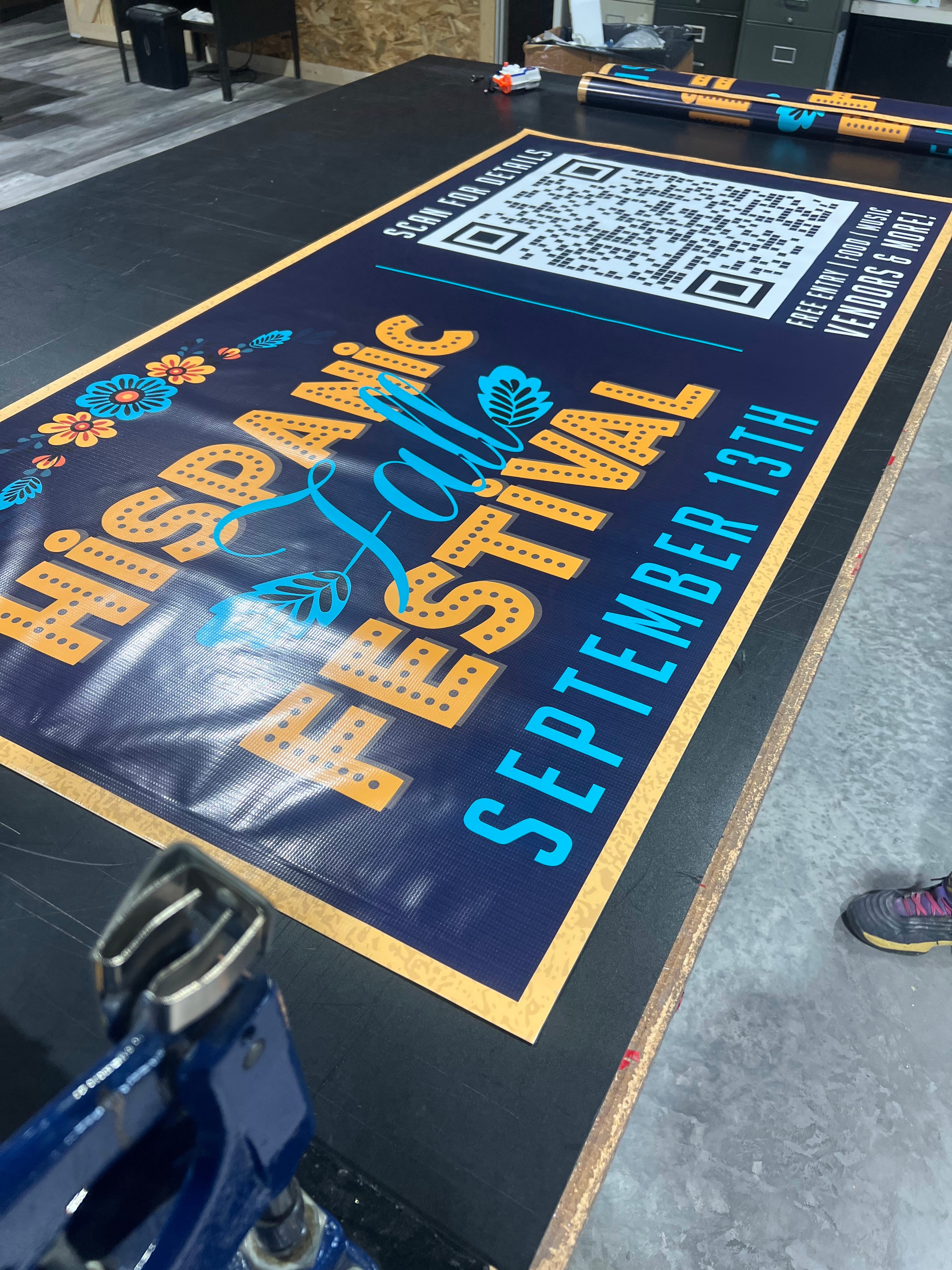 Hispanic Fall Festival vinyl event banner with QR code and event date being finished in the shop